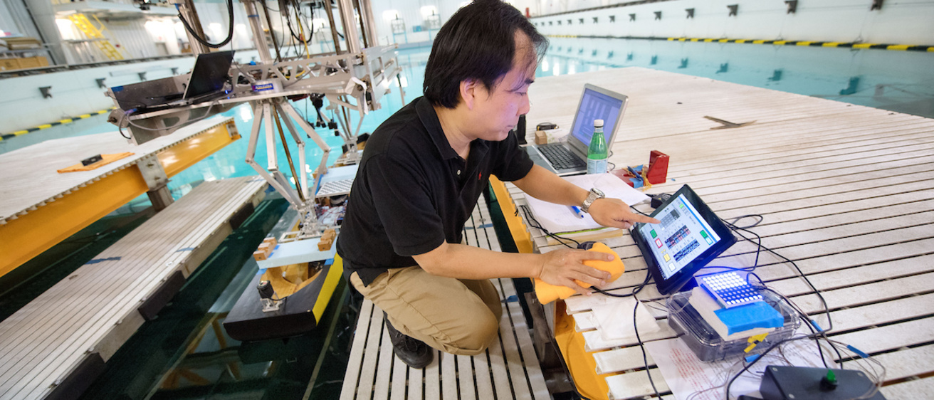 A researcher works on computers on the edge of the wave basin