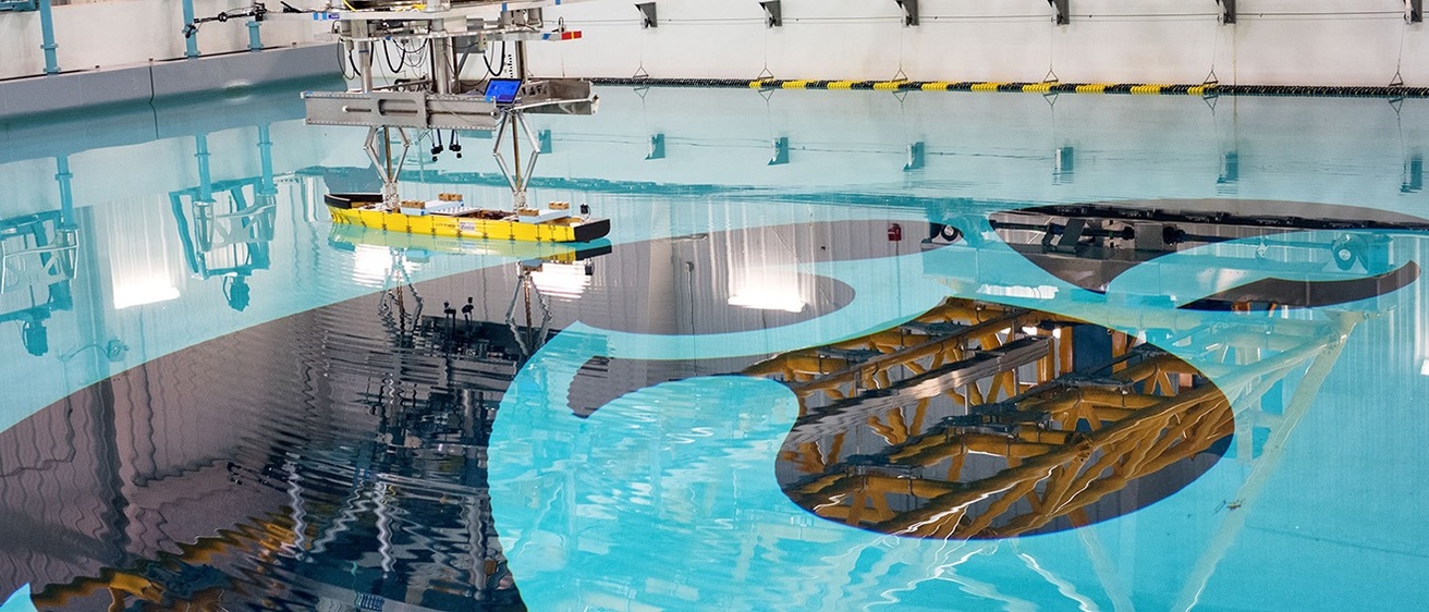 A model-scale ship floats above a giant Tiger Hawk logo in the IIHR wave basin